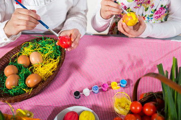 Close up of little girl and mother coloring eggs for Easter