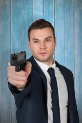 Composite image of serious businessman pointing a gun