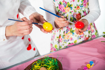 Close up of little girl and mother coloring eggs for Easter