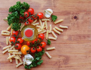 pasta, herbs, oil, tomatoes and on a wooden