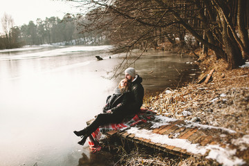 Couple sitting on pier at frozen lake looking at each other