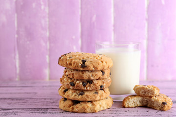 Tasty cookies and glass of milk on color wooden background