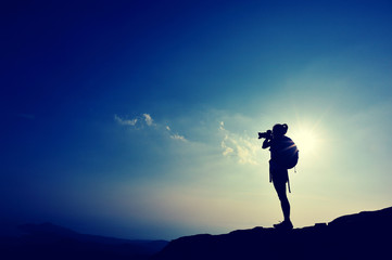 woman photographer taking photo on seaside mountain peak