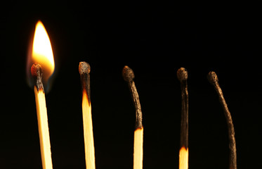 Burnt and burning matches on black background