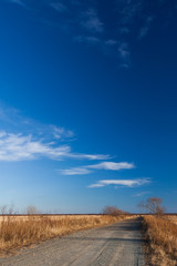 Rural road through the field. Sky and cloud