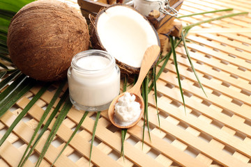 Coconut with leaf and cosmetic cream in jar on wooden