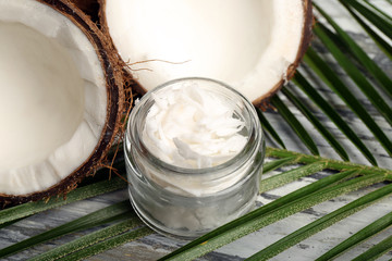 Coconut with leaf and jar of coconut oil on table close up