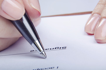 Closeup of young female signing contract