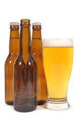 Tall glass of cold beer with brown beer bottles isolated on white background photo