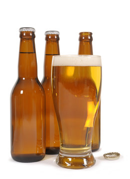 Tall glass of cold beer with brown beer bottles isolated on white background photo