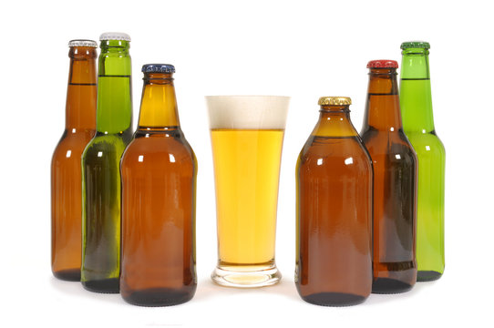 Tall glass of cold beer with several different shape beer bottles isolated on white background photo