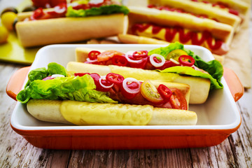 Grilled hot dogs with ketchup, mustard and relish on a table bac