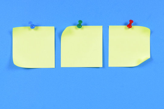 Row or line of three yellow post it style sticky note pinned to blue background photo