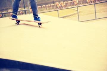 Fototapeta na wymiar skateboarder legs skateboarding at skatepark ramp 