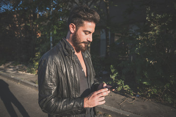 Fototapeta premium young handsome attractive bearded model man using smartphone