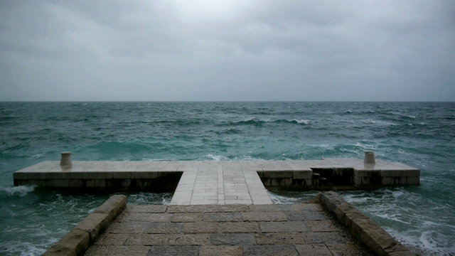 Rough weather at sea and waves crashing to the stone pier