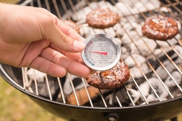 Man using meat thermometer while barbecuing