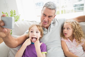 Obraz premium Father making face while taking selfie with children
