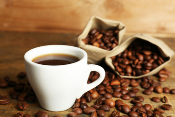 Cup of coffee with beans on rustic wooden background