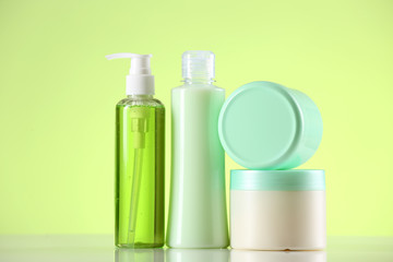 Cosmetic bottles on light green background