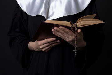 nun hands holding bible book over grey