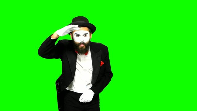 Man mime looks for something and uses binoculars on green screen