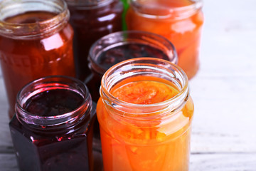 Homemade jars of fruits jam on color wooden planks background