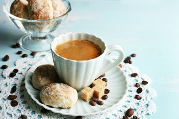Cup of coffee and tasty cookie on color wooden background