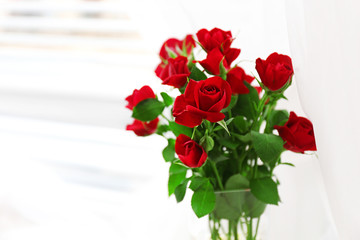Bouquet of red roses in glass vase on curtain background