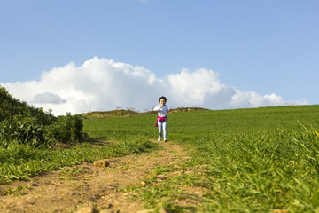 Niña corriendo y caminando feliz por el camino en el campo