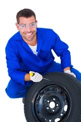 Portrait of happy mechanic working on tire