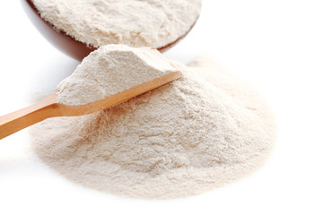 Flour in bowl and wooden spoon isolated on white