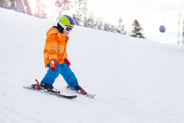 Skiing boy in ski mask, helmet on mountain slope