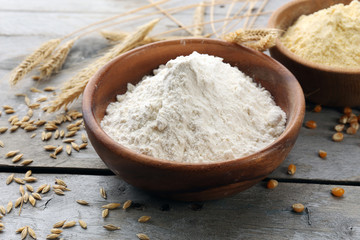 Fototapeta na wymiar Flour in bowls with grains on wooden background