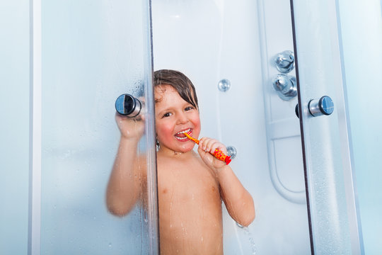 Little boy brush teeth with toothbrush in shower