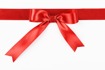 Red satin ribbon with a bow on a white background