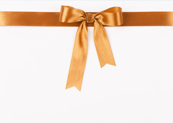 Gold satin ribbon with a bow on a white background