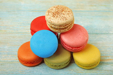 Tasty colorful macaroons on color wooden background