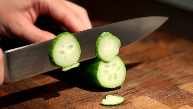 Female hands chopping cucumber