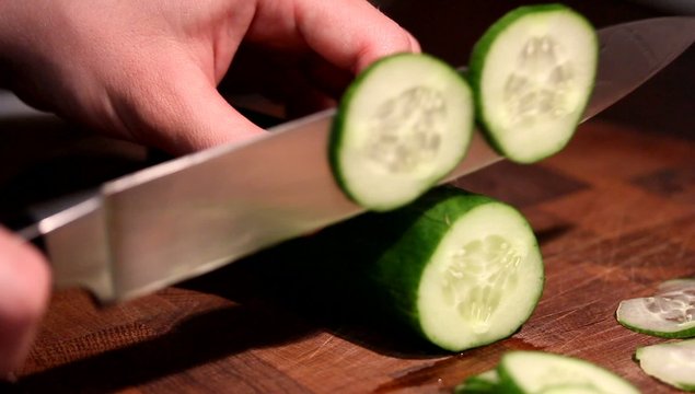 Female hands chopping cucumber