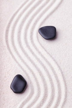 Zen garden with a wave lines in the sand with relaxing black sto