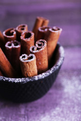 Cinnamon sticks in small bowl with powdered sugar