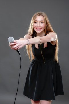 Portrait of a beautiful blonde young woman singing into micropho