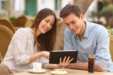 Couple watching media in a tablet in a restaurant