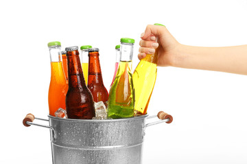 Female hand taking bottle of drink from bucket isolated on white