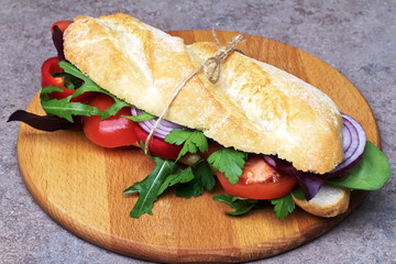 Sandwich with tomatoes, bell pepper,red onion and arugula.