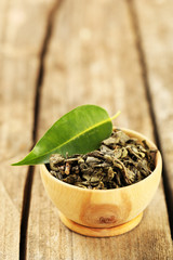 Green tea with leaf in bowl on old wooden table