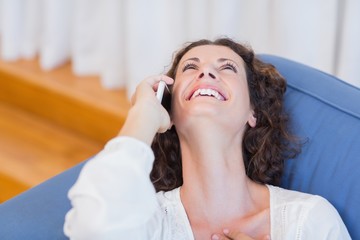Smiling woman sitting on the couch and using her smartphone