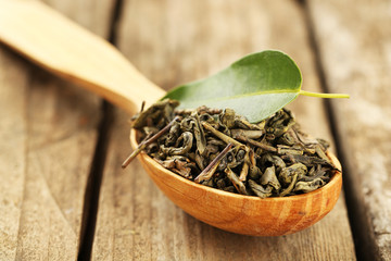 Green tea with leaf in spoon on old wooden table