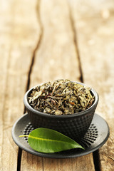 Green tea with leaf in cup on old wooden table